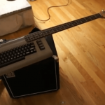 The C64 electric bass guitar pictured on top of an Ampeg combo amp.